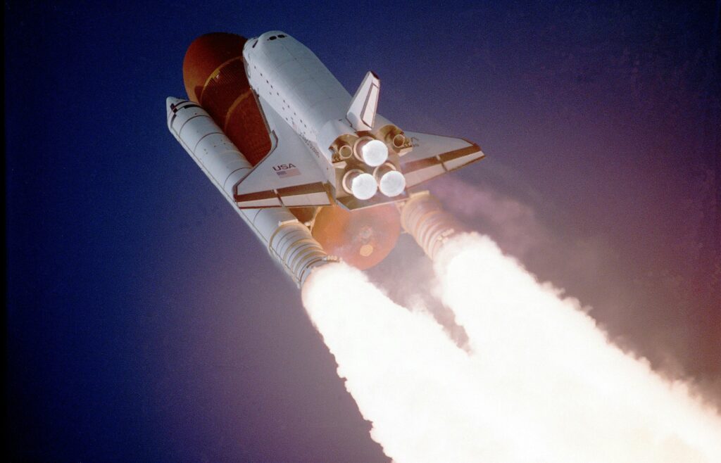 flight-sky-earth-space-2159 - IOblend A space shuttle launches into space, showcasing powerful rocket engines and USA branding.